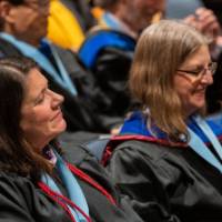 2 faculty women smile in the audience